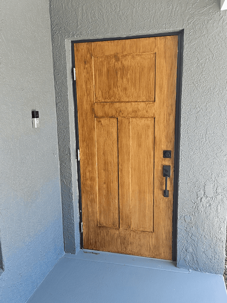 Wooden front door in gray stucco entryway