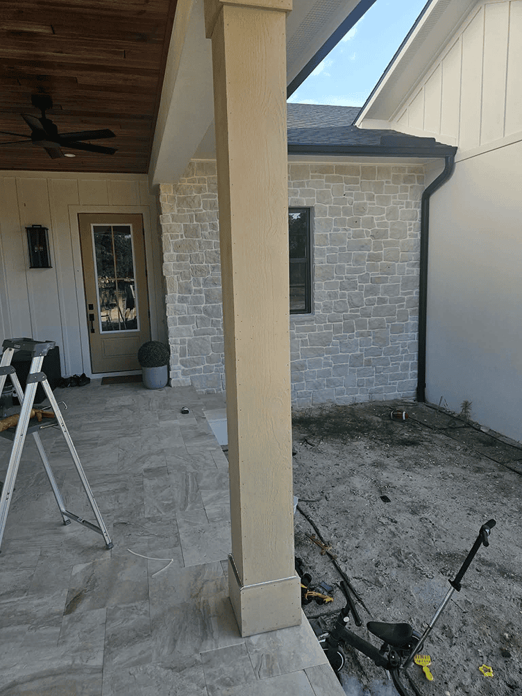 Covered patio with stone wall and lawnmower
