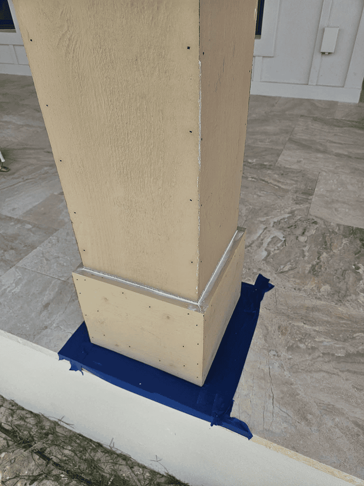 Beige porch column base with blue painter's tape